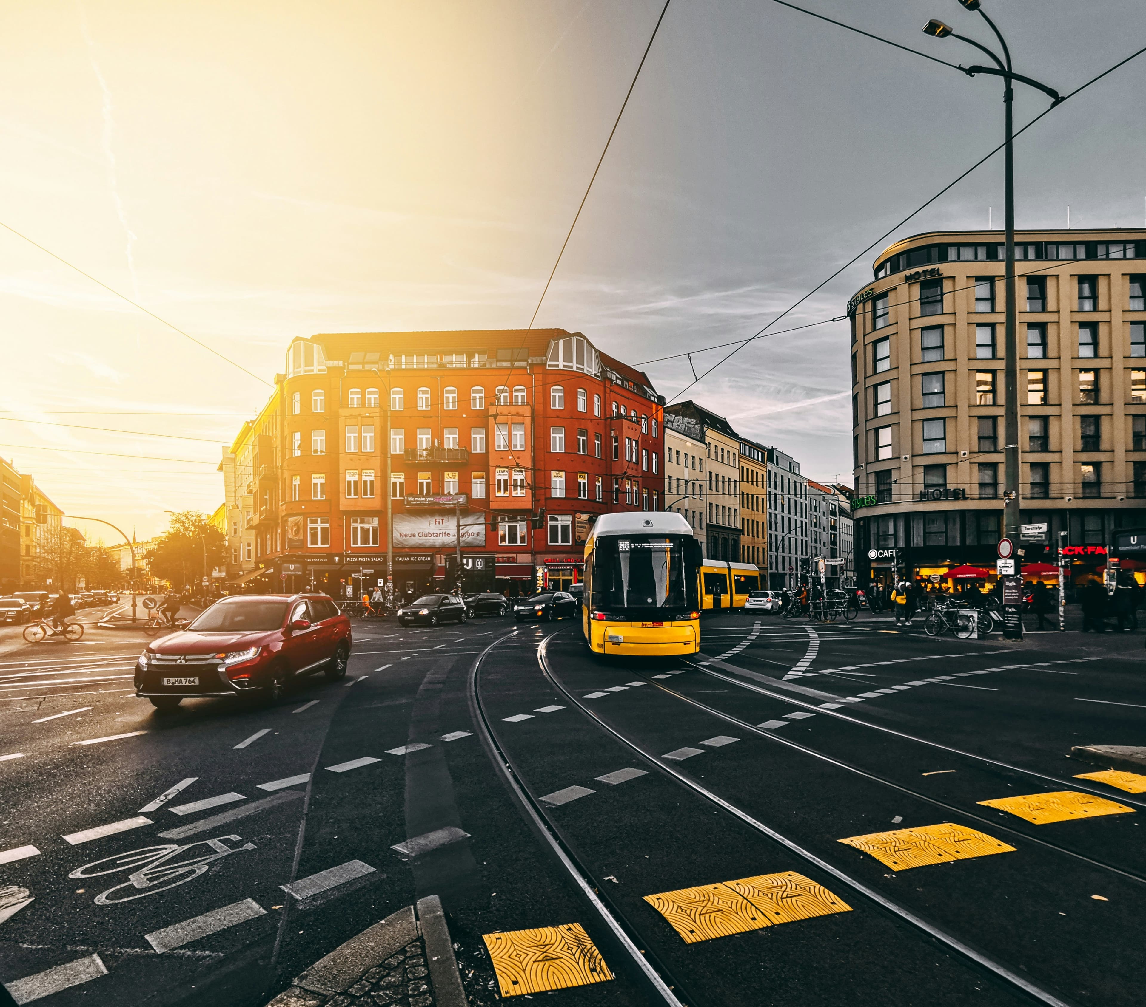 A yellow Berlin tram crossing a sunlit Mitte intersection at golden hour.